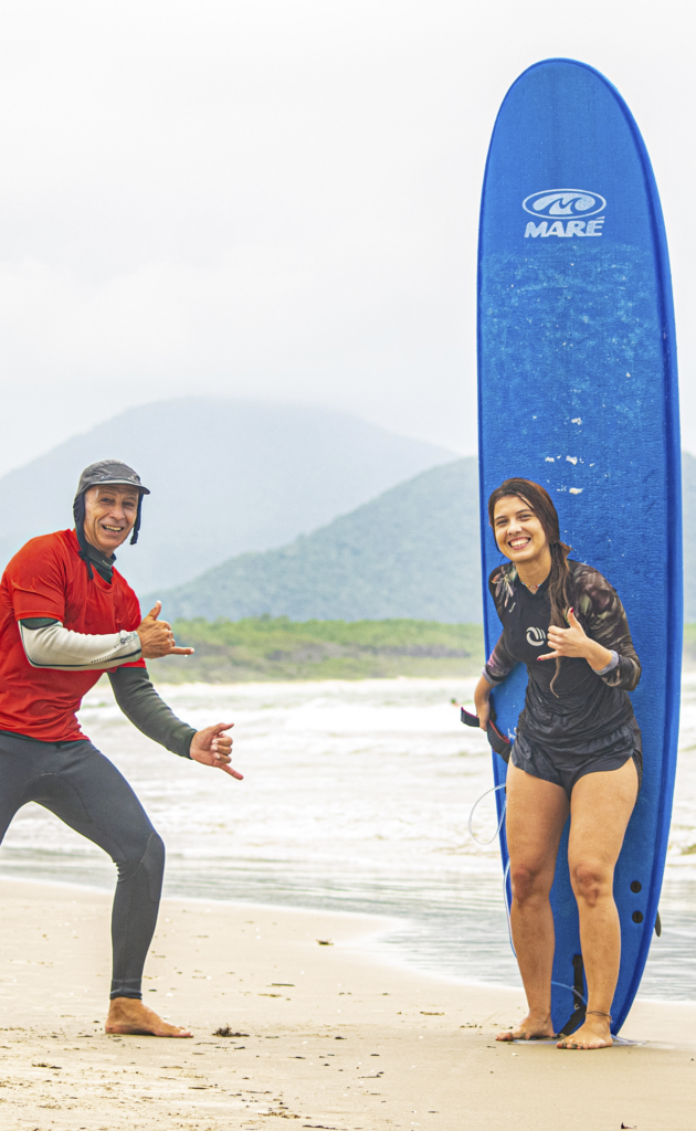 instrutor de surf ernesto e aluna mulher da nexus surf school em frente prancha, na areia da praia da barra da lagoa em florianopolis